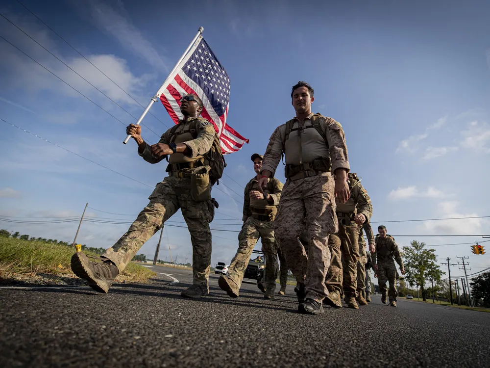 soldiers march carrying an American flag