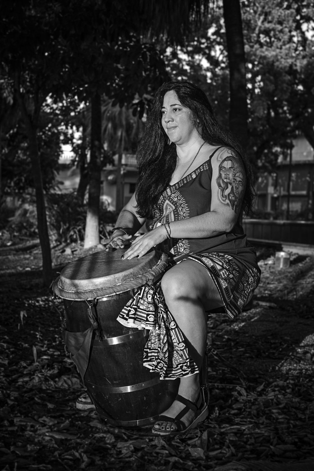 a black and white portrait of a woman in a dress sitting at a drum