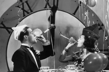 A 1930s couple rings in the new year with party blowers and streamers. New Year's Eve celebrations only began incorporating countdowns decades later, with the first crowd countdown in Times Square taking place in 1979.