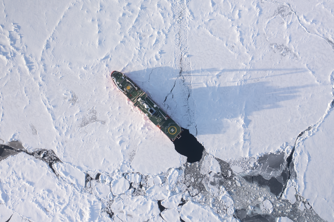 An aerial view of an enormous 'icebreaker' ship cutting through a patch of white ice