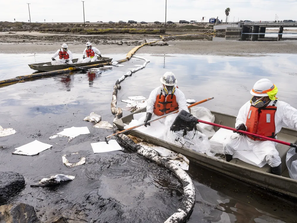 Workers with Patriot Environmental Services mop up oil on the surface of the water at Talbert Marsh in Huntington Beach, CA on Monday, October 4, 2021.