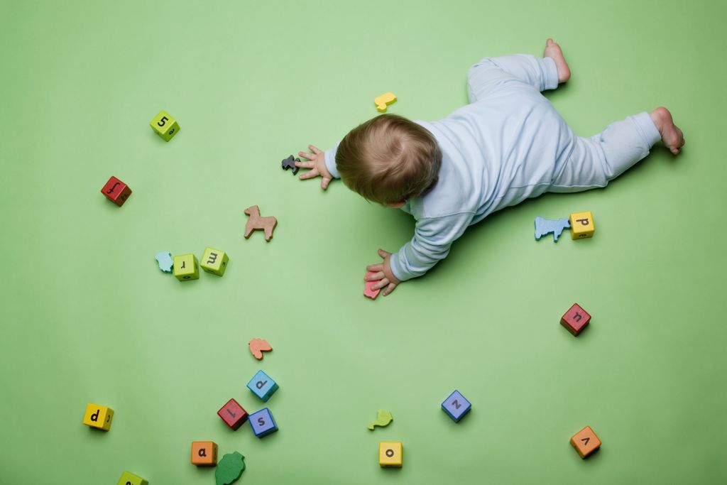 Aerial view of a baby on all fours playing with blocks