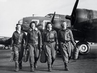  Carrying their parachutes, Women Airforce Service Pilots (left to right) Frances Green, Margaret Kirchner, Ann Waldner, and Blanche Osborn pass a line of Boeing B-17s at a U.S. Army airfield in Columbus, Ohio, where in 1944 they were training to ferry the bombers.