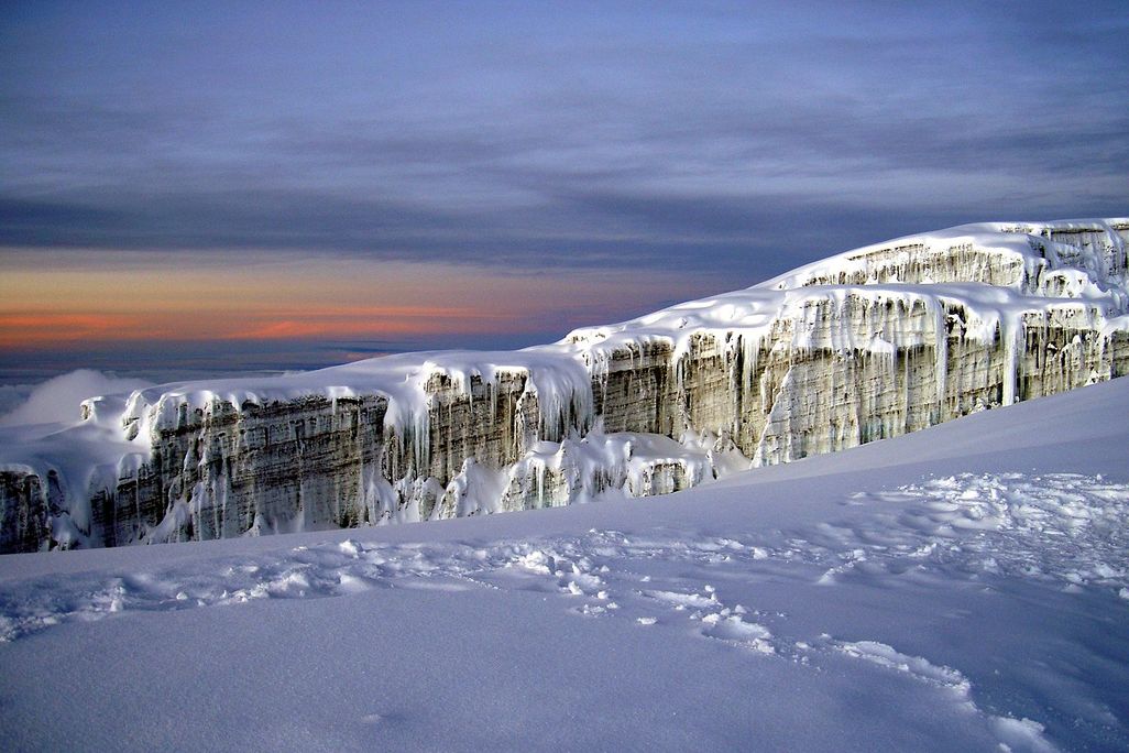 The face of a jagged white glacier on top of a snowy mountainside