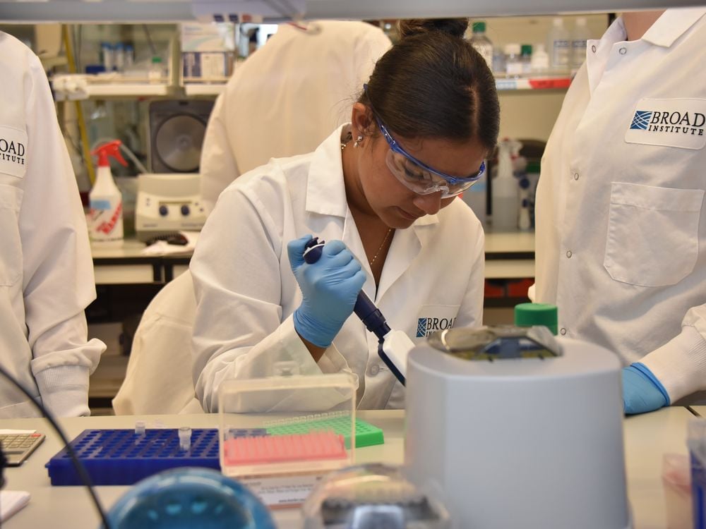 A young girl wears a lab coat, safety goggles and blue latex gloves in a research laboratory