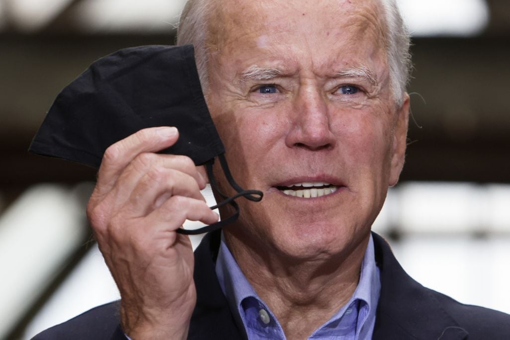 An image of President Joe Biden holding up a black mask as he speaks.