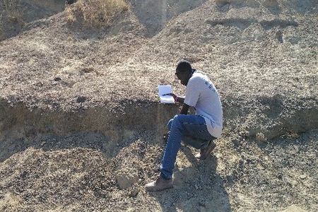 Sylvester Musembi Musyoka, a Kenyan colleague and field crew leader, recording a large mammal fossil bone during a virtual field project to collect fossils in Kenyan excavation sites that were in danger of being damaged by severe weather. 