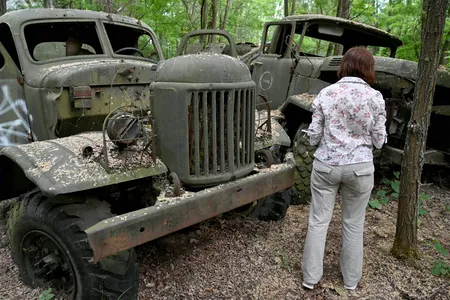 A woman looks at wreckage of trucks in the ghost city of Pripyat during a tour in the Chernobyl exclusion zone on June 7, 2019.