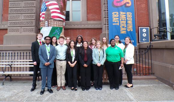 A group of teens stand in front of the Renwick Building for a group photo