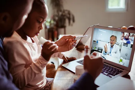 A father and his daughter engage in a video chat with their doctor.