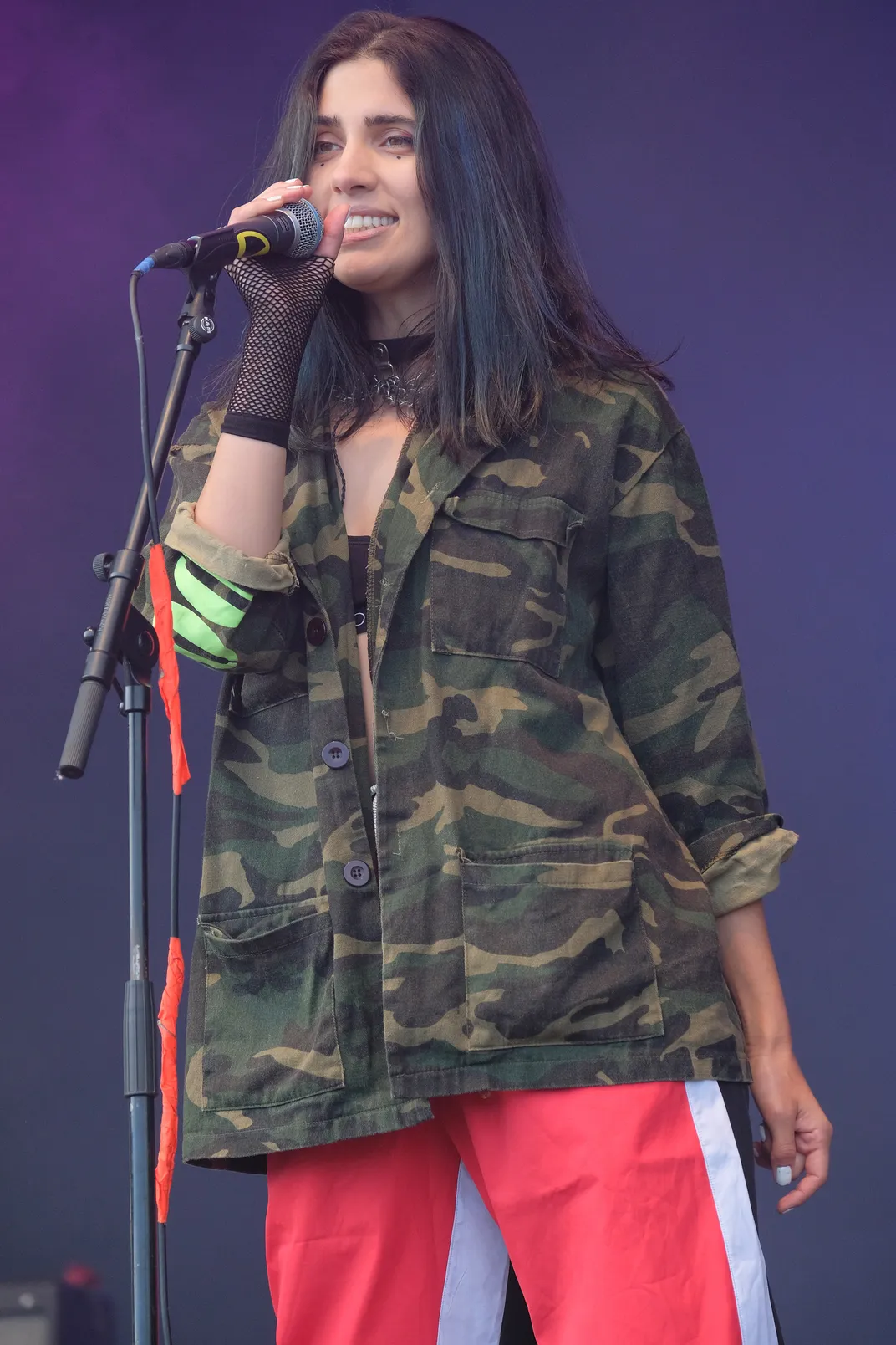 young Russian girl in red pants and camouflage jacket singing into microphone