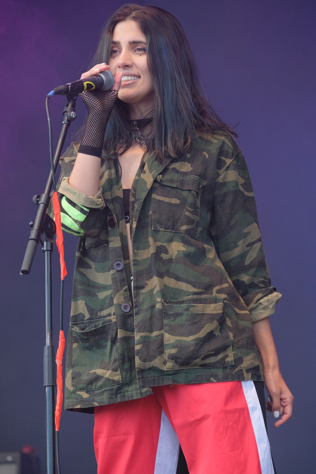 young Russian girl in red pants and camouflage jacket singing into microphone