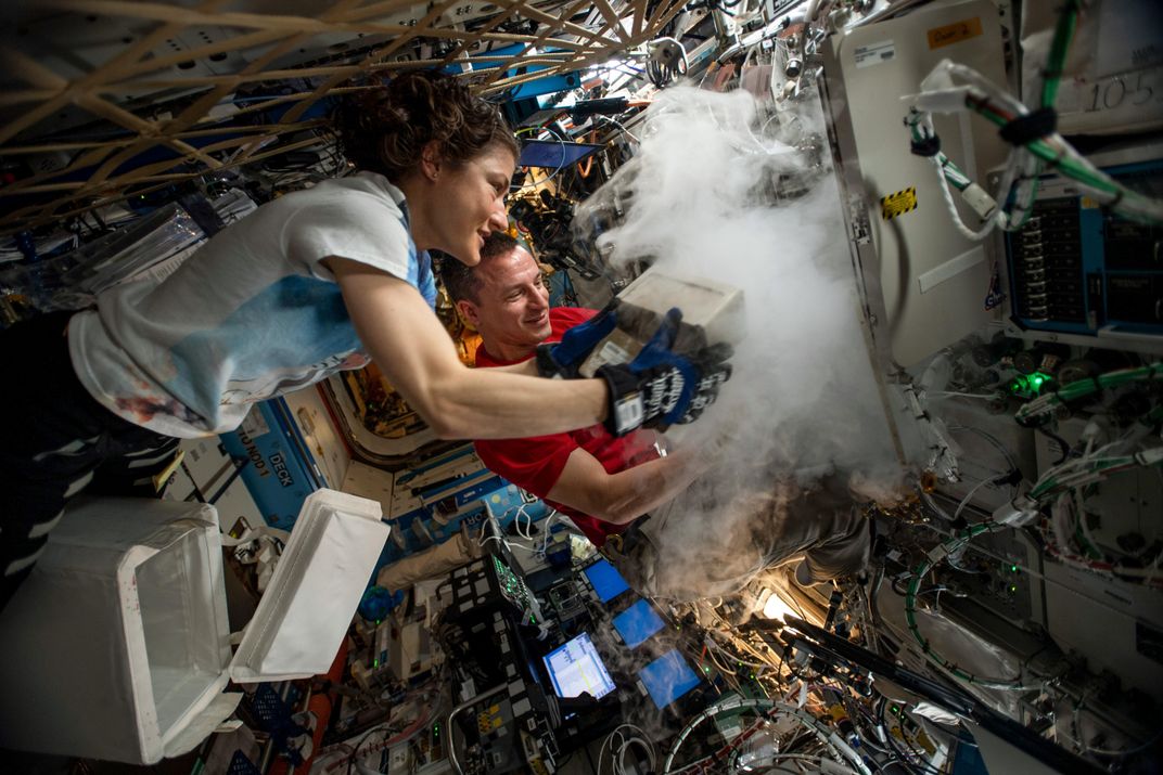 Christina Koch and Drew Morgan put samples in a science freezer