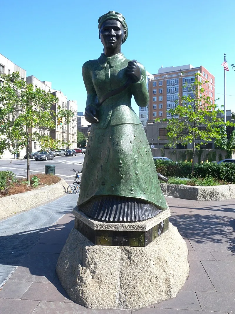 A copper statue of Harriet Tubman, who strides forward as the bottom of her dress becomes a boat