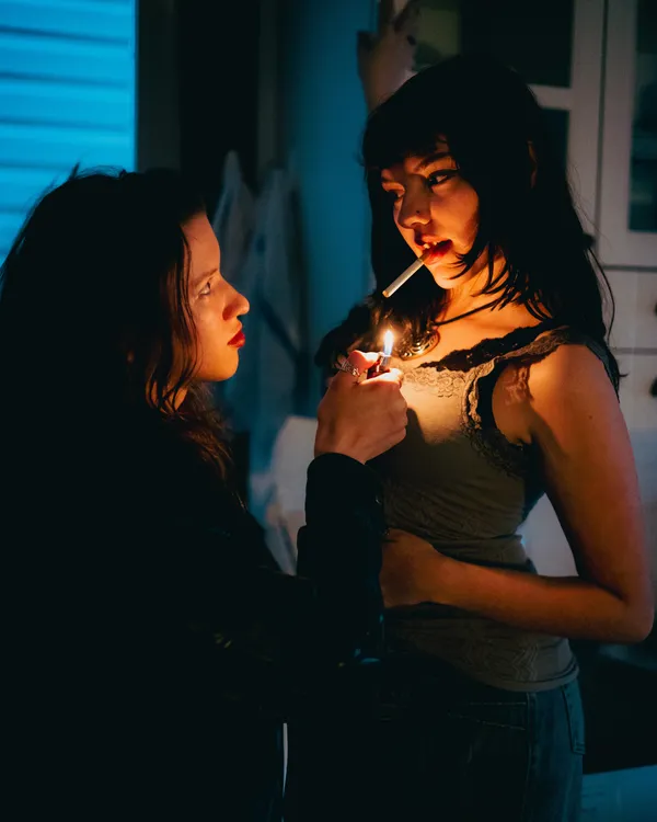 A woman lights her partner's cigarette. thumbnail