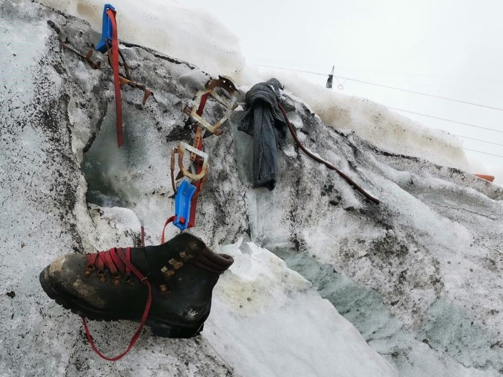 Hiking boot dangling from snow with other gear nearby