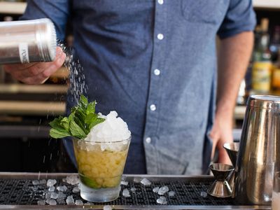 Bartender making mint julep cocktail.
