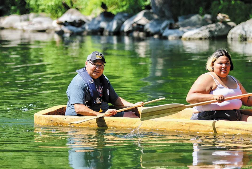 two people paddle in a dug out canoe