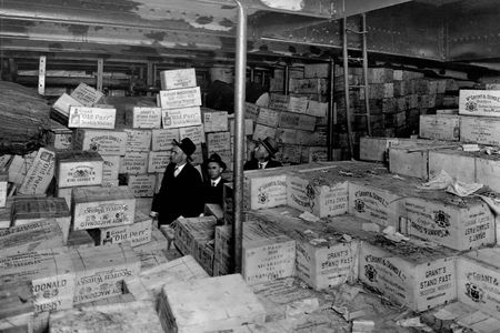 Aboard the Coast Guard Cutter USS Seneca, Prohibition agents stand amidst cases of scotch whiskey confiscated from a "rum runner" boat.