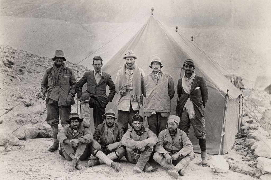 black and white photo of nine men in front of a tent