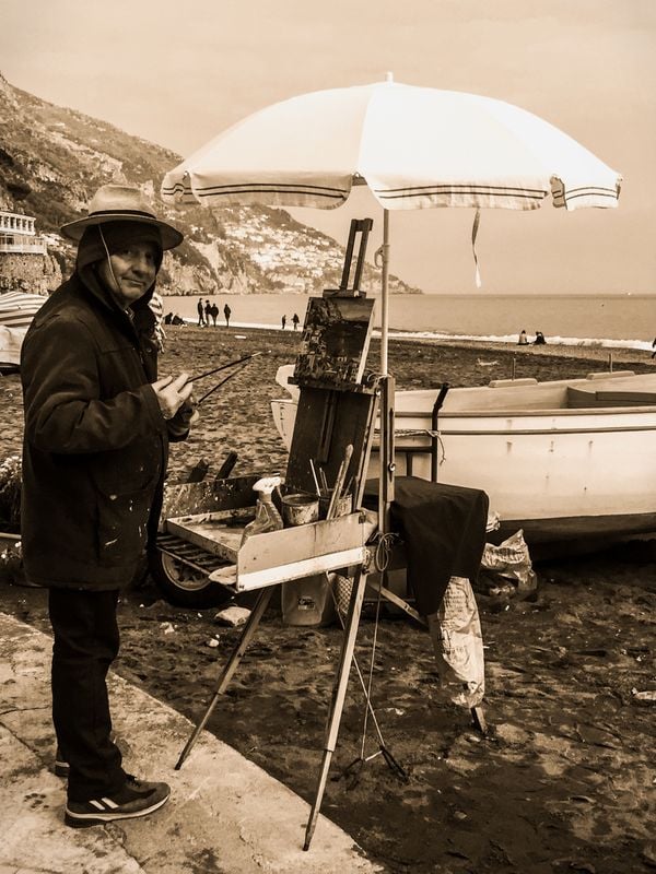 An old man painting the coast of a cloudy Positano thumbnail
