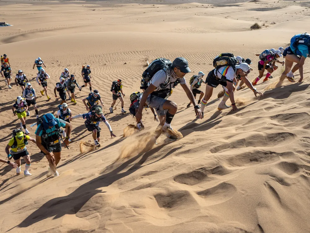 Runners climbing a sand dune