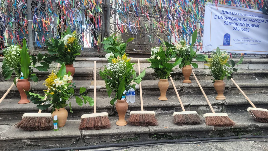 brooms, flowers in vases and water bottles sit on a staircase outside of a church