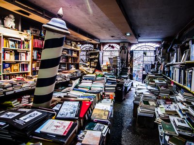 A gondola, piled high with books, sits in the middle of the shop.