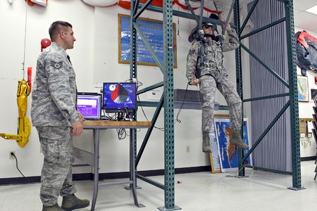 A U.S. Air Force Survival, Evasion, Resistance, and Escape specialist trains on PARASIM. The parachute straps and steering controls connect to sensors that adjust the simulation displayed inside the trainee's virtual reality helmet.
