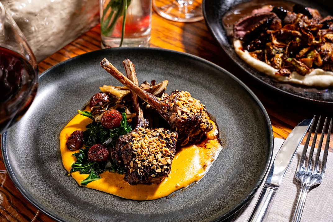 its handsome dining rooms serve some toothsome dishes, including this almond-crusted rack of lamb with carrot and feta purée.