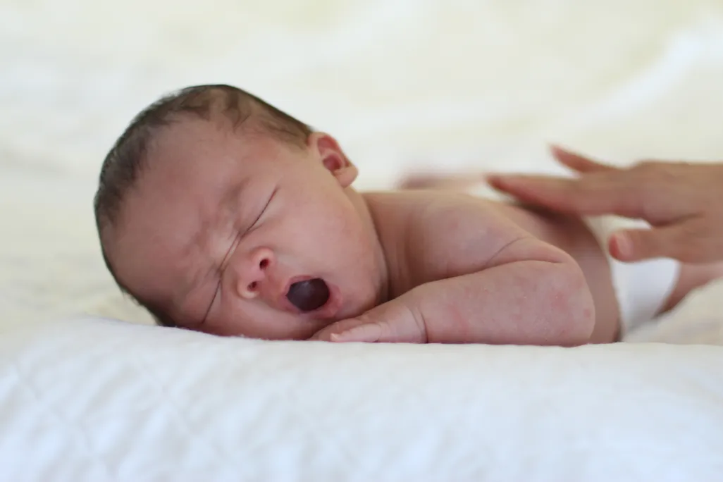 A baby laying on its stomach yawning