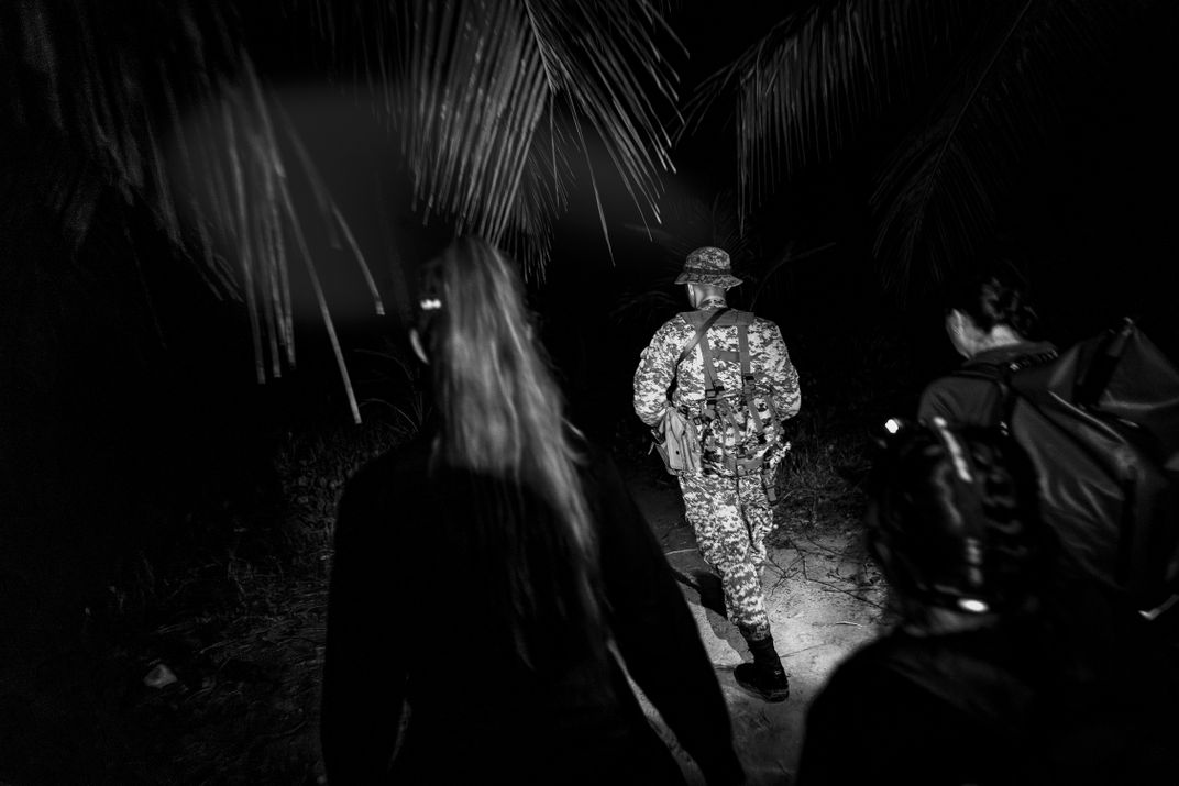 Researchers on a nocturnal patrol, accompanied by an armed guard. Sea turtles crawl ashore at night to lay their eggs, so scientists seek them out in the dark.