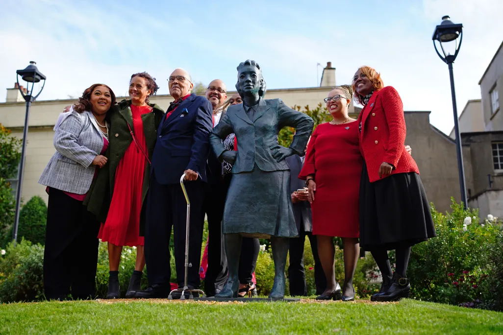 Henrietta Lacks' family stands an grass on either side of a life-sized statue of her