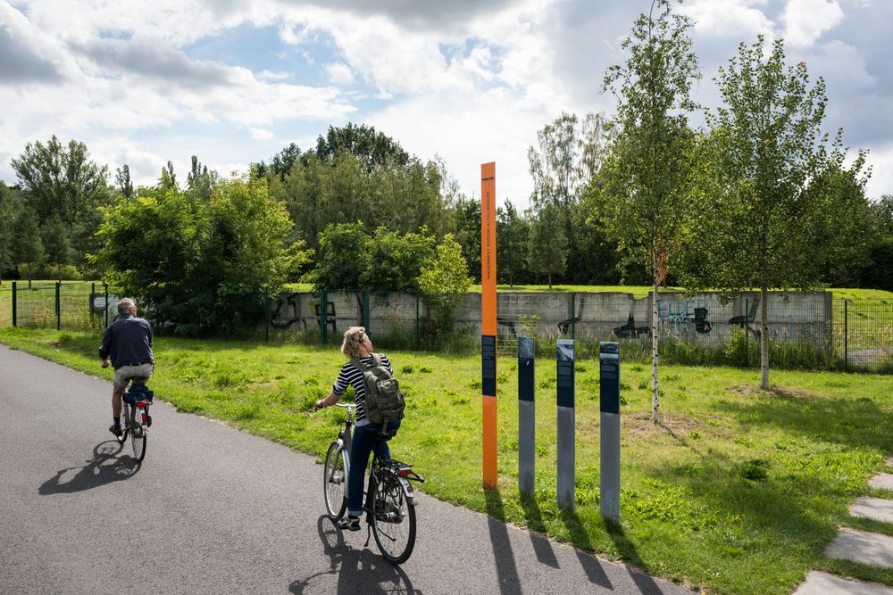 cyclists pass a preserved section of the Berlin Wall