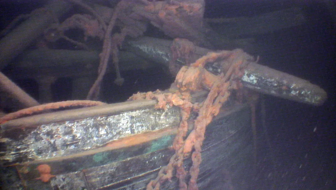 A view of a ship's bow underwater, with rusted chains and siding visible