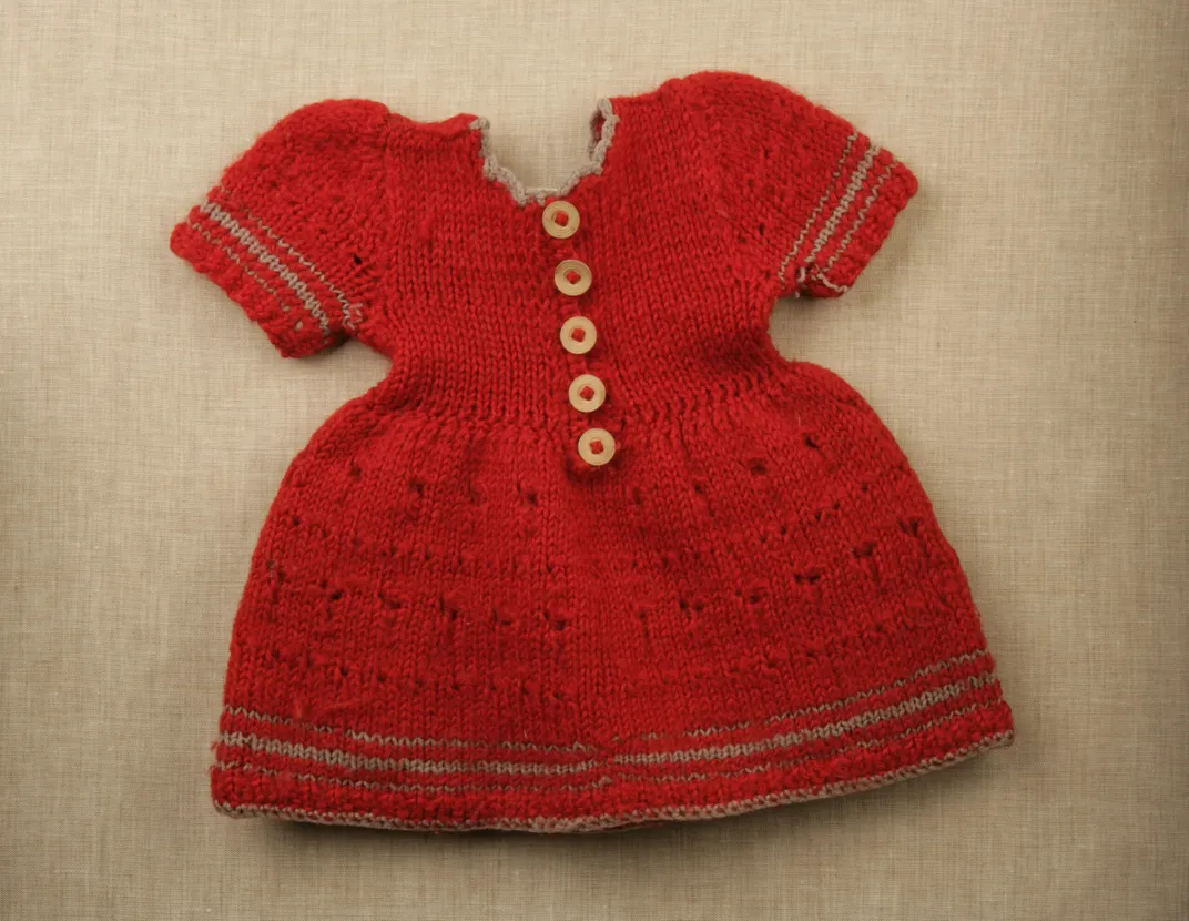 A small red dress with white buttons and gray edging