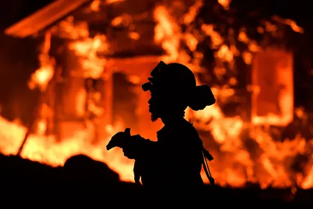 An inmate firefighter monitors flames as a house burns in the Napa wine region of California on October 9, 2017.