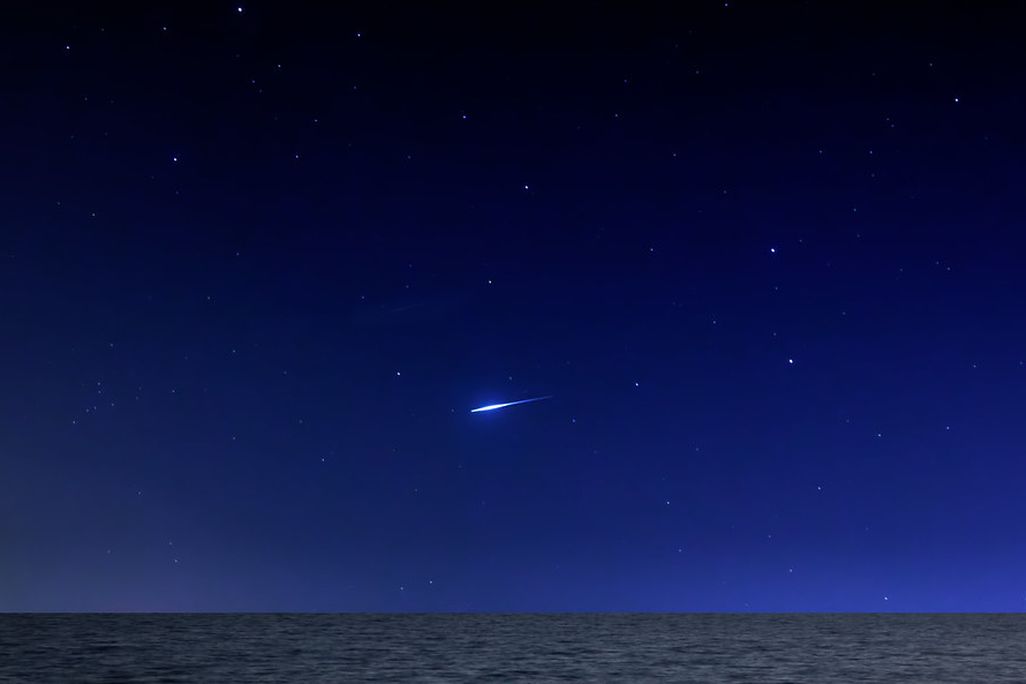 Meteor streaking across dark sky with stars