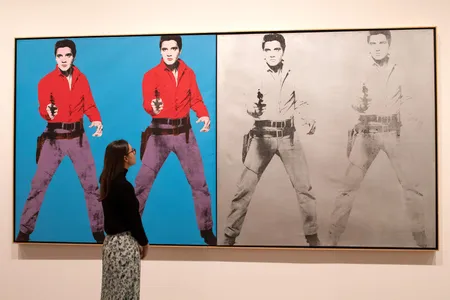 A gallery assistant poses with Andy Warhol's Elvis 1 and 2 1963-4 during a press preview for Tate Modern's retrospective on March 10, 2020.