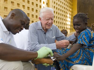 Jimmy Carter tries to comfort 6-year-old Ruhama Issah at Savelugu Hospital in Ghana as a Carter Center technical assistant dresses Issah&#39;s Guinea worm wound. In May 2010, Ghana reported its last case of Guinea worm disease and announced it had stopped transmission a year later.