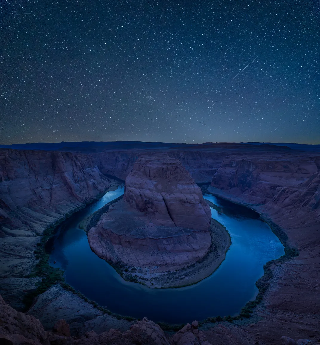 A starry night sky reflects light off the shallow waters of Horseshoe Bend in Glen Canyon National Recreation Area