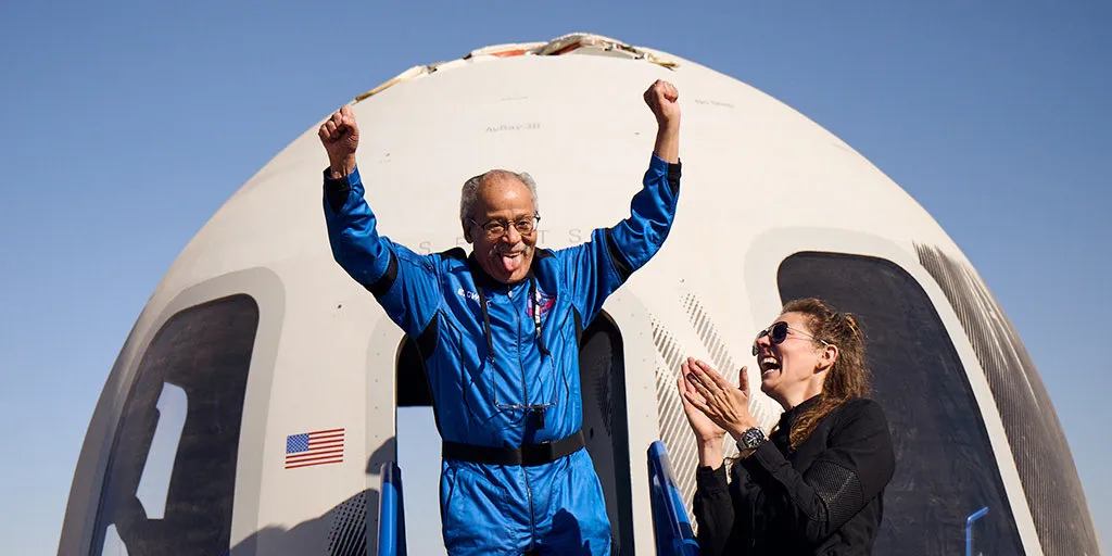 Ed Dwight raises arms outside capsule