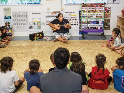 students in a circle while teacher strums ukelele