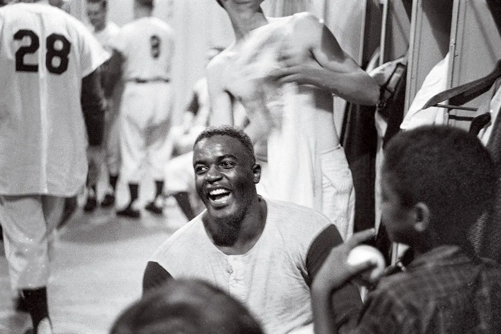 Jackie Robinson smiling in a locker room