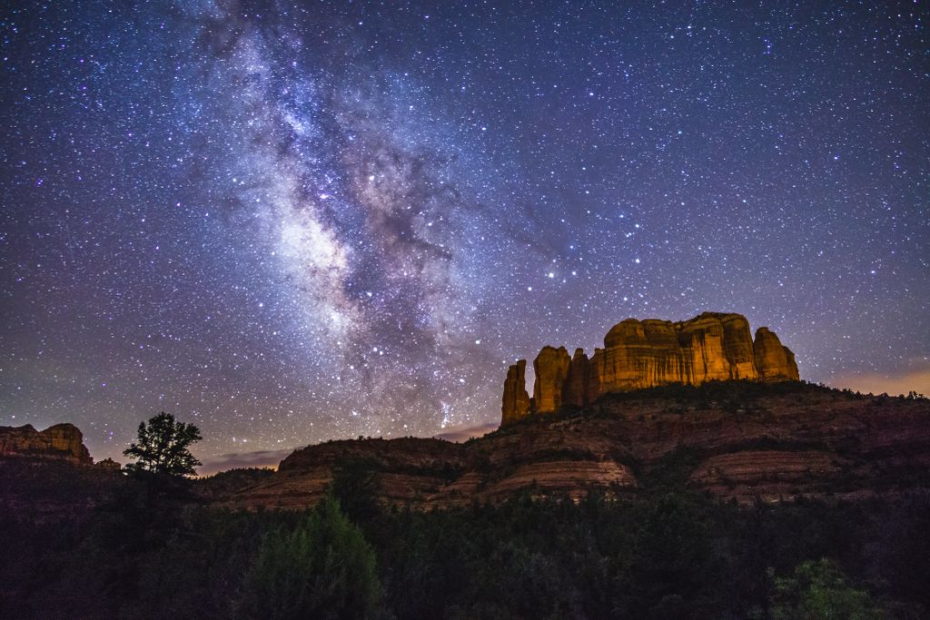 milky way over a rock formation on a mountain