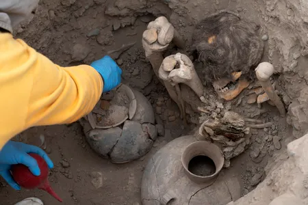 A worker uncovers the mummy, which belonged to the Ychsma culture, buried in a shallow funeral chamber during an excavation in the Huaca Pucllana on September 5, 2023.