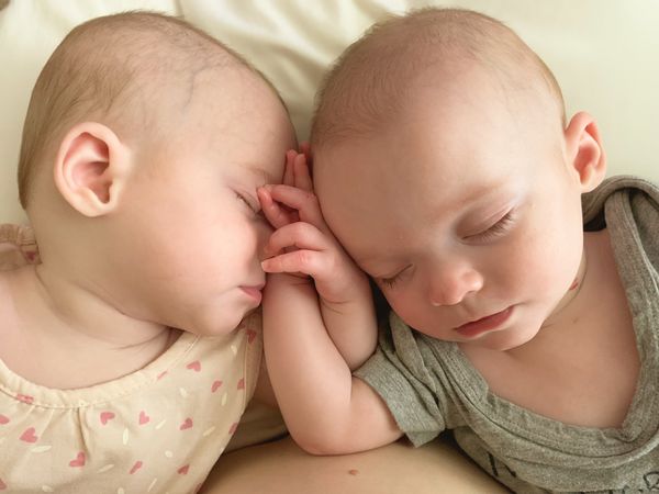 Identical twins hold each other close. thumbnail