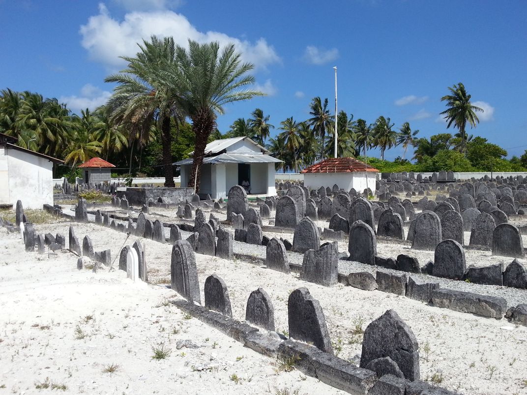 A view of a cemetery surrounded by white sand and palm trees