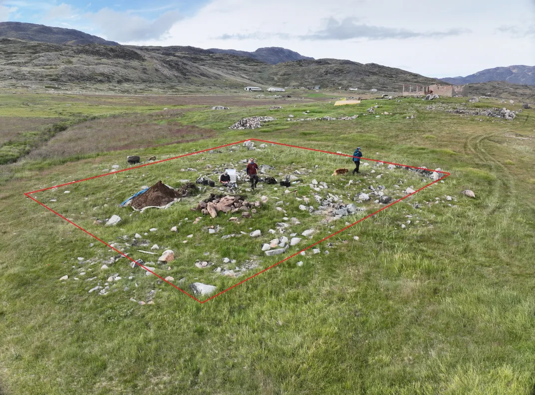 Archaeologists standing on a grassy area with stones