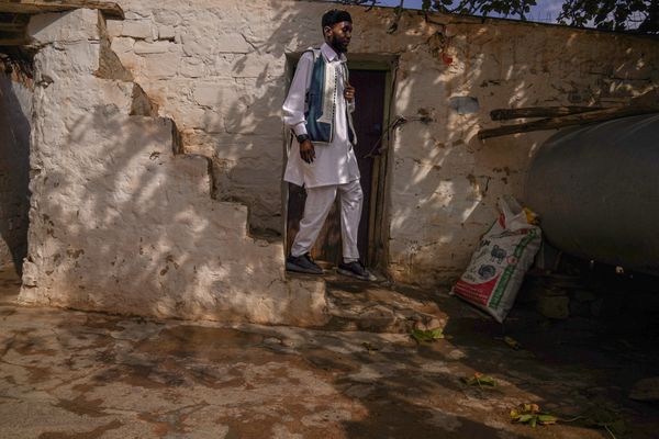 Man in Traditional Dress Exiting a Rustic Dwelling thumbnail